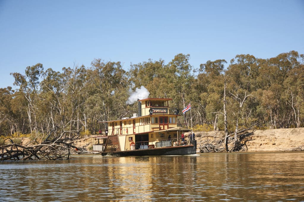 PS Emmylou paddle steamer cruising along the Murray River with bushland in the background on a sunny day.