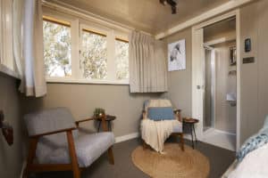 Interior of a PS Emmylou cabin with comfy armchairs, ensuite bathroom and natural light from river-facing windows.