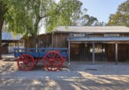 Traditional timber building with a vintage blue and red cart outside, part of a heritage site near the Murray River.