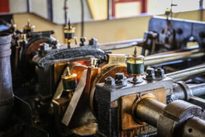 Close-up of the vintage steam engine inside the PS Emmylou, showing polished brass and mechanical components in operation.